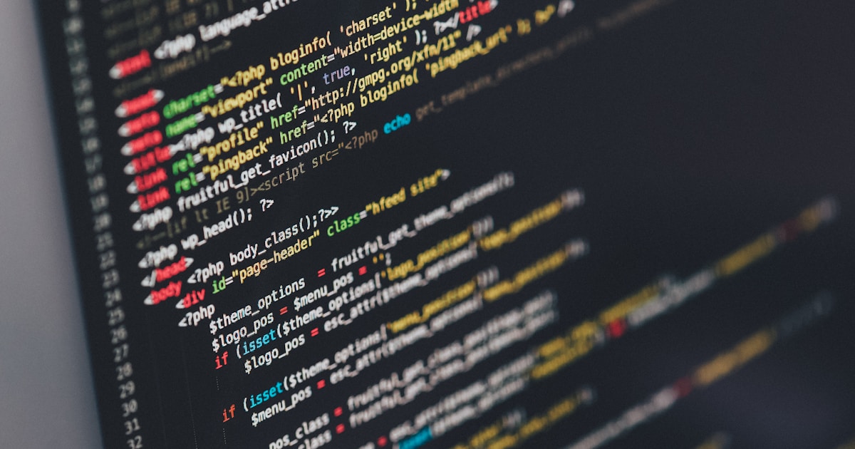 Developer coding at desk with multiple monitors showing code